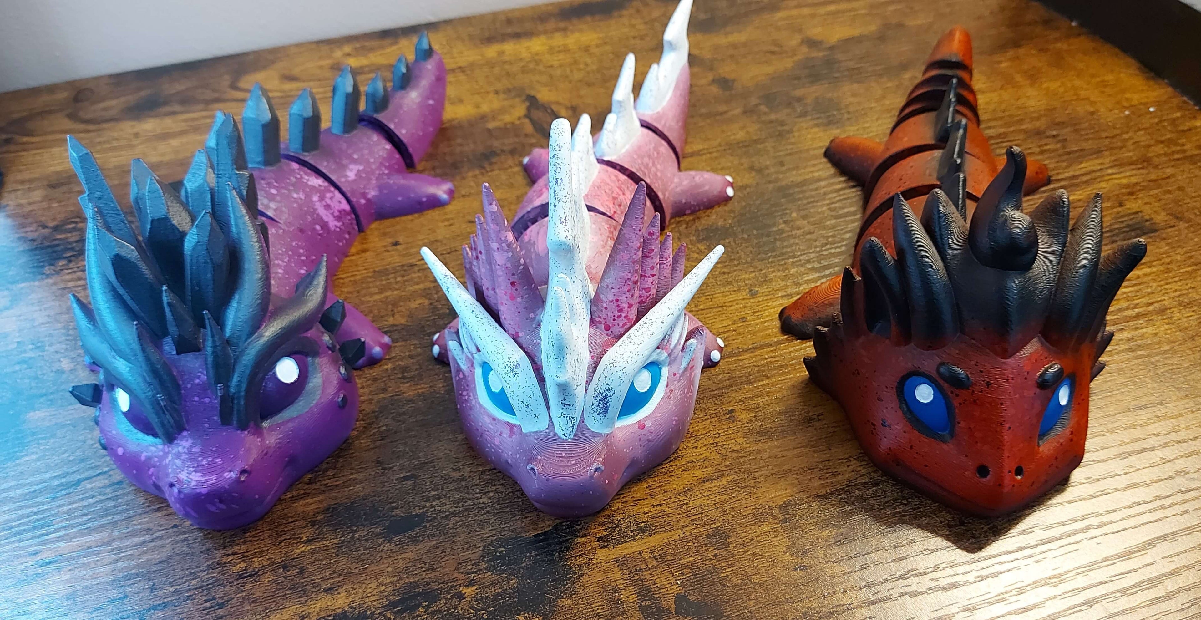 Group of custom large dragon figurines in purple, pink, white, and red, hand-painted and 3D-printed by Kylyne’s Custom Treasures.