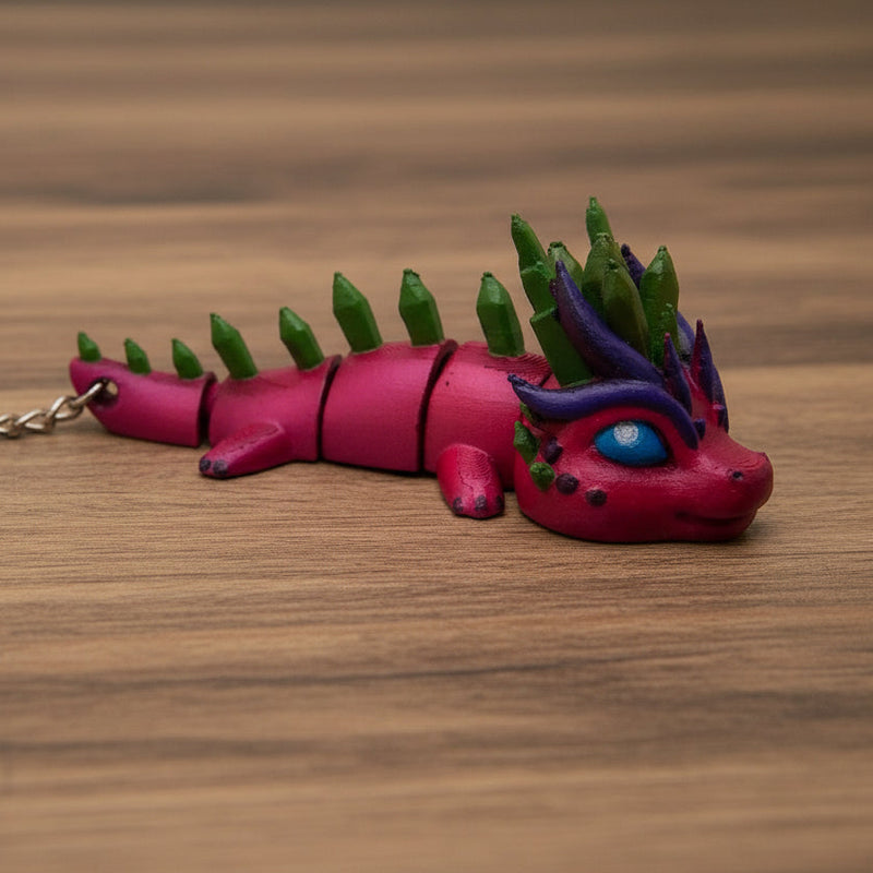Pink dragon-shaped keychain with green spikes on a white background