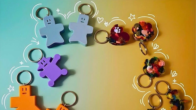 Colorful 3D-printed keychains and dopamine dangles on a yellow background with playful doodles.