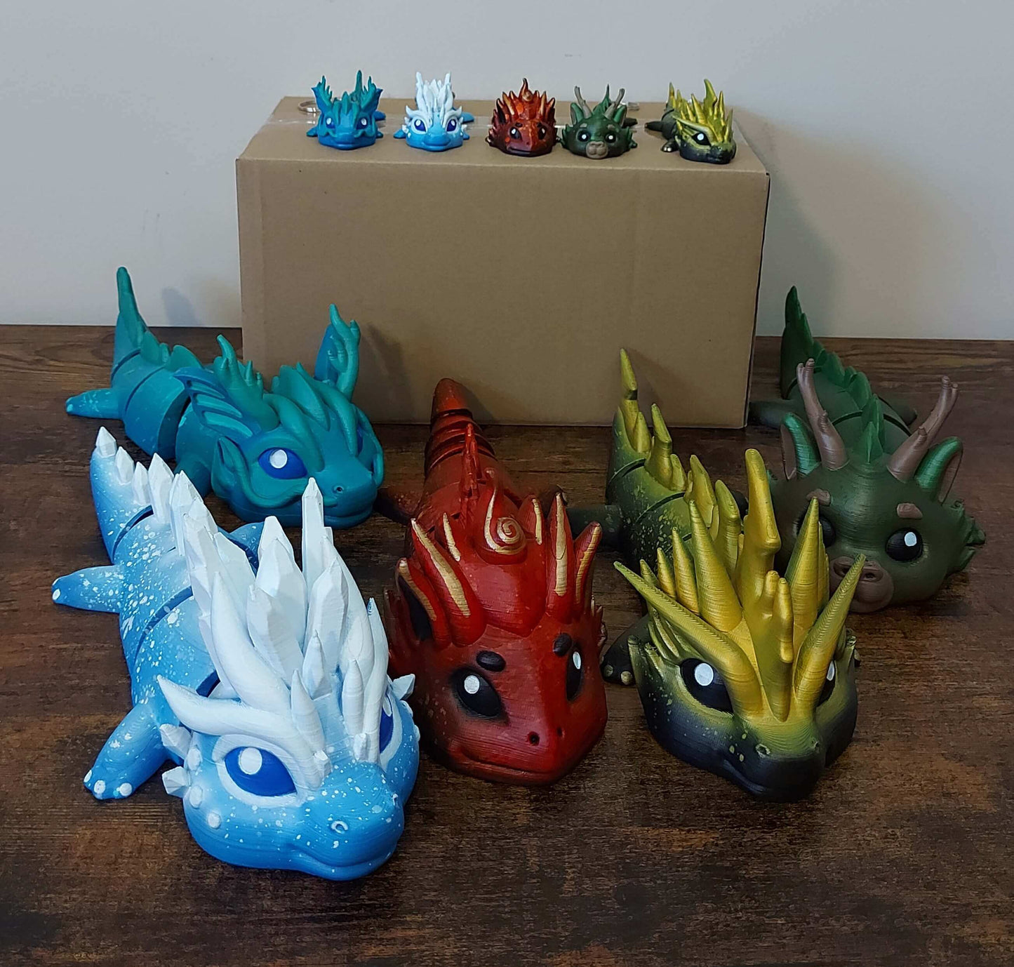 Five hand-painted elemental dragons - sea, ice, fire, forest, and thunder - articulated fidget companions crafted for neurodivergent minds by Kylyne's Custom Treasures