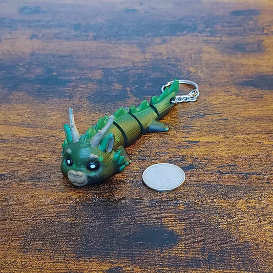 Keychain size Dasyra the Forest Elemental Dragon of Drakora, 3D-printed and hand-painted by Kylyne’s Custom Treasures, displayed on a wood background with a coin for scale.