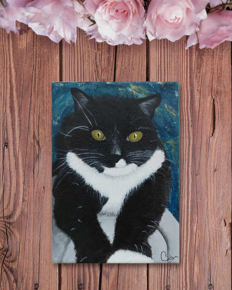 Custom hand-painted cat portrait of Willow, a black and white tuxedo cat with bright yellow eyes, created by Kylyne’s Custom Treasures. Artwork displayed on a wooden background with pink roses above.