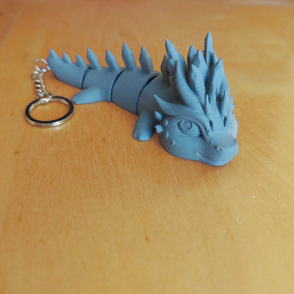 Primed Eryndra dragon keychain from the Paint Your Dragon Kit before painting, shown on a wooden surface.