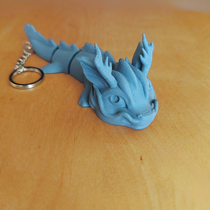 Primed Vaylen dragon keychain from the Paint Your Dragon Kit before painting, shown on a wooden surface.