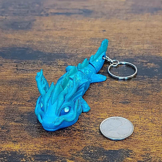 Keychain size Vaylen the Sea Elemental Dragon of Drakora, 3D-printed and hand-painted by Kylyne’s Custom Treasures, displayed on a wood background with a coin for scale.